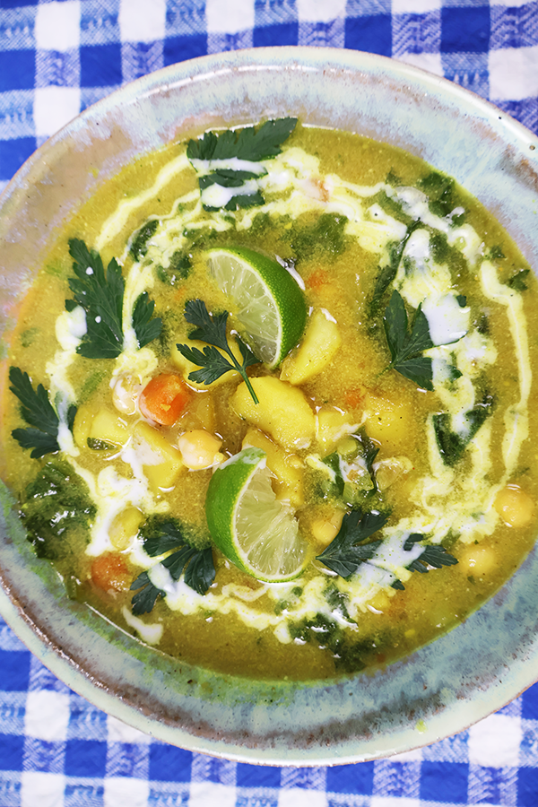 Zbliżenie na szary talerz. W talerzu kolorowa zupa z dodatkiem fasoli, ciecierzycy, marchewki, limonki, pietruszki i śmietany.