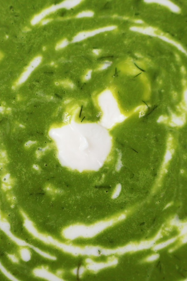 Zbliżenie na zieloną zupę z dodatkiem śmietany.