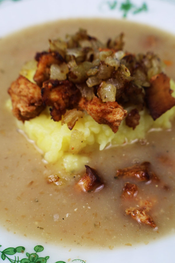 Zbliżenie na zupę z kopką ziemniaków i skwarkami z tofu i cebuli.